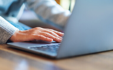 Closeup image of a woman working and touching on laptop computer touchpad on the table