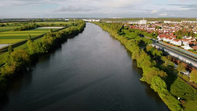 Aerial view overlooking the Main river and the Raunheim town, during golden hour, in Germany - dolly, drone shot