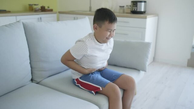 Overweight Asian boy suffering from stomachache at home