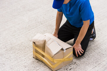 Asian young delivery man in blue uniform he emotional falling courier hold damaged cardboard box is...