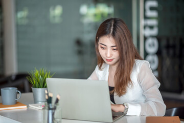 Young asian business woman beautiful charming smiling and using laptop computer in modern office.