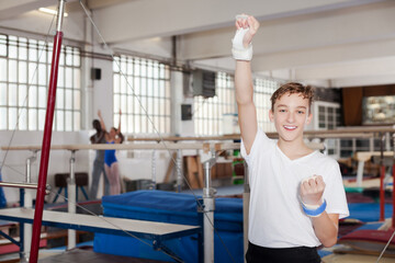 Fototapeta na wymiar Happy teenage athlete rejoicing at her sporting success at gymnastic hall.