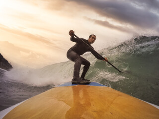 Adventurous Man Surfing the waves at the Pacific Ocean in Oregon Coast. Dramatic Colorful Sunrise...
