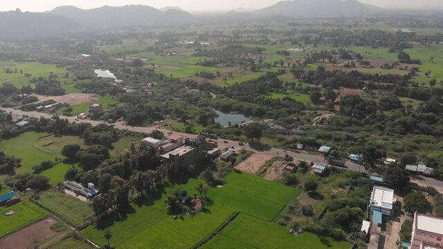 Lush green landscape surrounding Tindivanam Highway at midday as traffic passes by