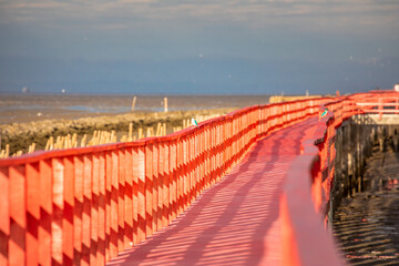 Obraz premium Golden natural sea sunrise view of Mangrove forest and wooden bridge with orange sky landscape at Bangkhuntien, Bangkok, Thailand.