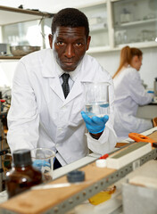 Serious male scientist with test tubes checking for result of chemical experiment