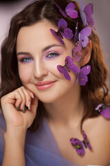 Beautiful young woman with artificial butterfly in curly hair.