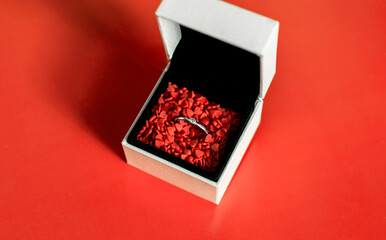 Ring in a white box on a red background. Photo taken with selective focus and noise effect