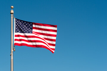 Picturesque perfect American flag blowing in the breeze over sky blue background with copy space 