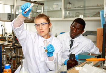 Focused woman lab technician checking for result of experiment in laboratory