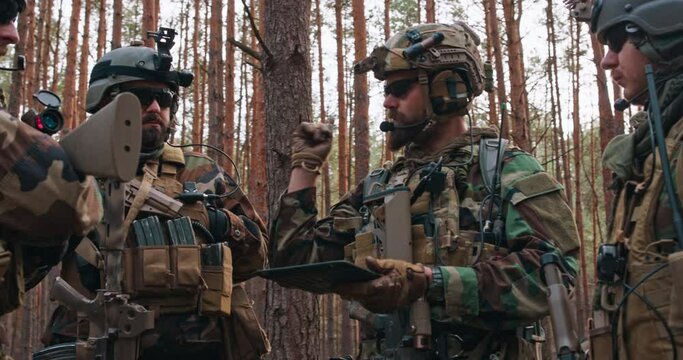 Squad Leader Discusses Military Operation Details with Soldiers, Commander Gives Orders. Fully Equipped and Armed Soldiers Ready for Mission in a Dense Forest.
