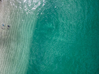 Clear blue ocean from above with a white sand beach