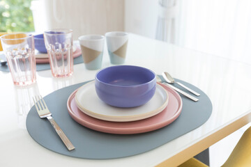 Beautiful table setting with pink and purple plate on table. Glassware and cutlery for catered event dinner.