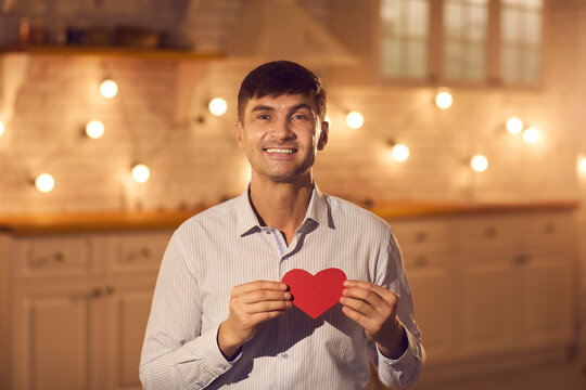 Smiling man boyfriend showing red decorative heart to his girlfriend during online dating