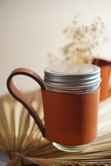 coffee mug on the white table , made from brown genuine leather
