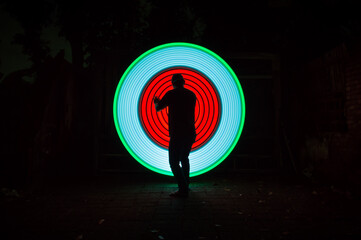 One person standing alone against a Colourful circle light painting as the backdrop