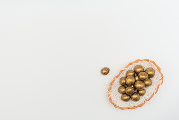 Golden chocolate Easter eggs in egg basket with white paper like a nest. Happy Easter holiday concept. Flat lay style with copy space.