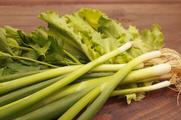 Bunch of fresh summer leeks, lettuce and parsley on a rustic wooden table.