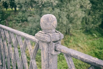 Naklejka premium Fence of an old forged metal bridge close-up against a background of green vegetation