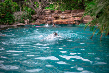 Waterfall blurred background That flows from the rocks, the garden decoration at the swimming pool is seen in the resort or hotel, allowing tourists to swim during the day.