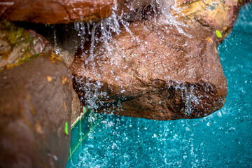 Waterfall blurred background That flows from the rocks, the garden decoration at the swimming pool is seen in the resort or hotel, allowing tourists to swim during the day.