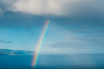 Fototapeta premium Rainbow coming out of cloud over ocean water