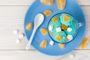 Fototapeta na wymiar top view of blue ice cream flavored with curacao syrup, citrus pieces and marshmallows on wooden table