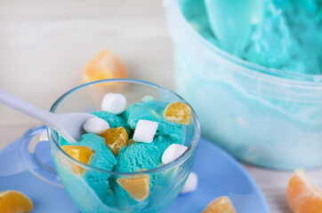 blue ice cream with tangerine pieces and marshmallows closeup