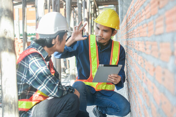 Two Engineer talking discussion tablet on site building construction