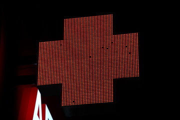 Glowing pixel cross of LED lamps on black background.