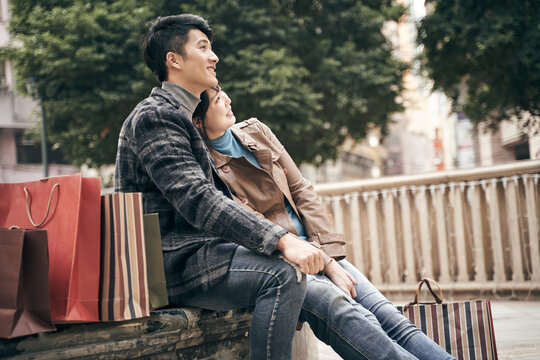 young asian couple relaxing outdoors while shopping in the city
