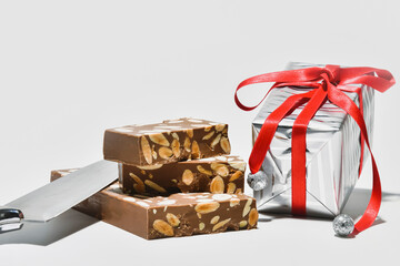 delicious chocolate and almonds nougat with a silver wrapped gift box and a kitchen knife
