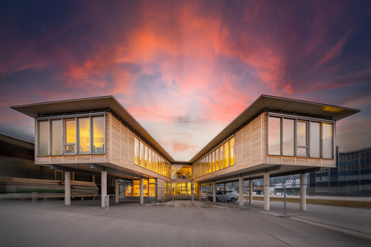 modern, sustainable office building with two wooden wings on concrete pillars at sunset