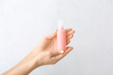 Female hands and travel bottle with body care cosmetics on white background
