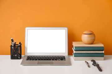 Stylish workplace with laptop near color wall