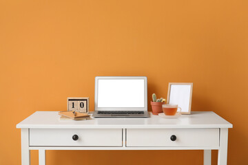Stylish workplace with laptop near color wall
