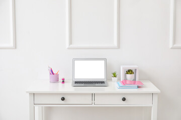 Fototapeta na wymiar Stylish workplace with laptop near white wall
