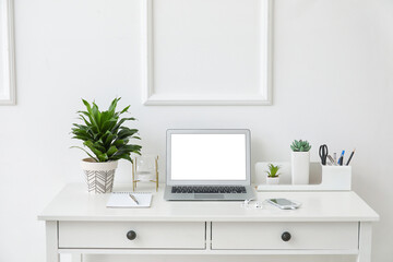 Obraz na płótnie Canvas Stylish workplace with laptop near white wall