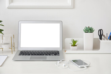 Stylish workplace with laptop near white wall