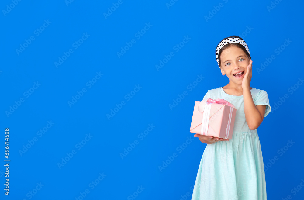 Poster Happy little girl with gift on color background