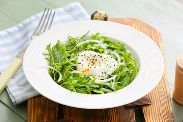 Plate with tasty arugula salad on wooden table
