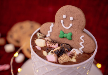 Delicious cup of hot chocolate with a gingerbread man cookie dipped in cinnamon sprinkled chocolates, ideal for a Christmas card.