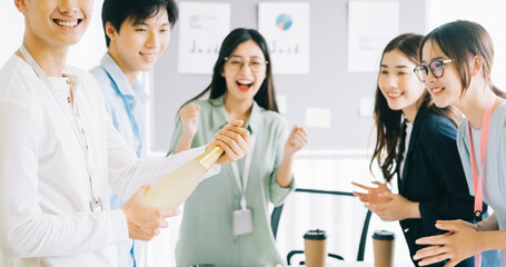 Asian businessman is opening champagne to celebrate the new year with the members of the business group
