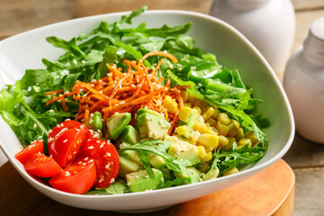 Bowl with tasty arugula salad on wooden table