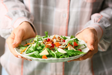 Woman holding plate with tasty arugula salad, closeup