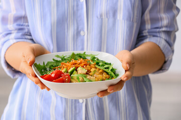 Woman holding bowl with tasty arugula salad, closeup
