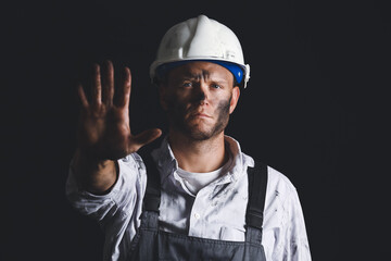 Miner man showing STOP gesture on dark background