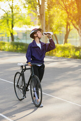 Obraz premium Female cyclist with bicycle drinking water outdoors