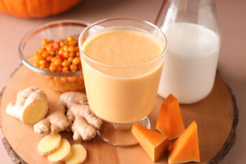 Glass of tasty pumpkin smoothie and bottle of milk on color background