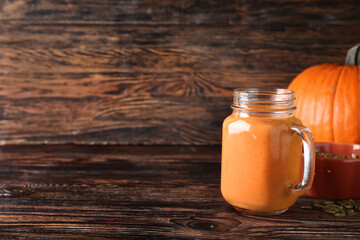 Mason jar of tasty pumpkin smoothie on table